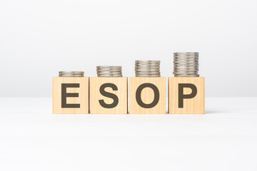 esop text written on wooden block with stacked coins on white background