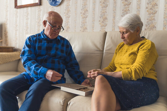 Senior European couple assembling wooden jigsaw puzzle together. Leisure time activities. Active retirement. High quality photo - Powered by Adobe