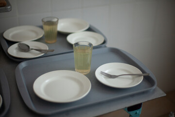 Fototapeta na wymiar Empty plates. Setting table in dining room. Kitchen details. School canteen in Russia. Cutlery on tray.
