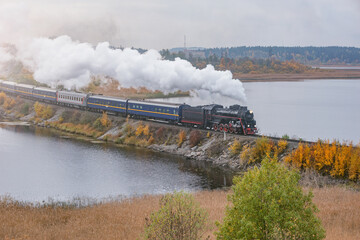 Fototapeta na wymiar Retro steam train moves along the lake.