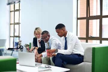 Teamwork will see them through the task. Shot of a group of businesspeople working together on a laptop in an office.