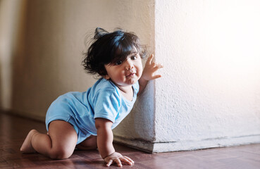 Looks whos around the corner. Shot of a little baby boy playing and hiding around a corner at home during the day.