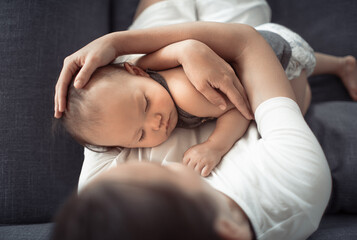 Fototapeta na wymiar Mother holding her baby sitting on sofa 