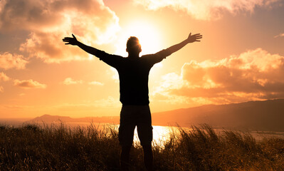 It's a beautiful life! Man standing in a field at sunset having feelings of freedom, hope, and...