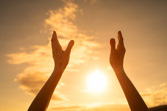 Woman with arm raised up to the sunrise at dawn. 