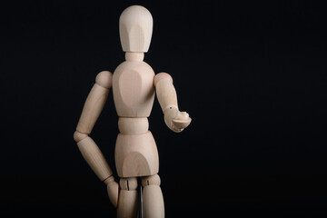 Human wooden figure holds in hands a zirconia bridge with glazour on a black background.
