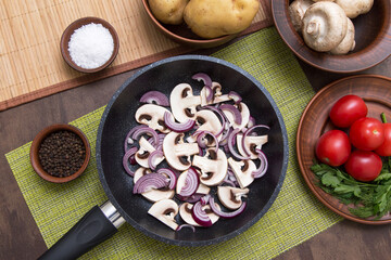 Cooking healthy vegan vegetarian food concept. Frying pan, sliced mushrooms and vegetables on kithchen table. Top view, flatlay