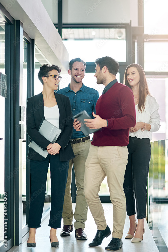 Poster together they make a great team. shot of a group of colleagues talking together in a large modern of