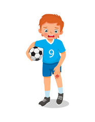 cute little boy has a knee injury crying holding his scratch bleeding leg with bruises after an accident fell down when playing soccer