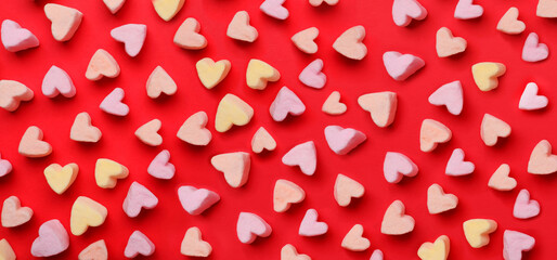 Many tasty marshmallows in shape of hearts on red background, top view