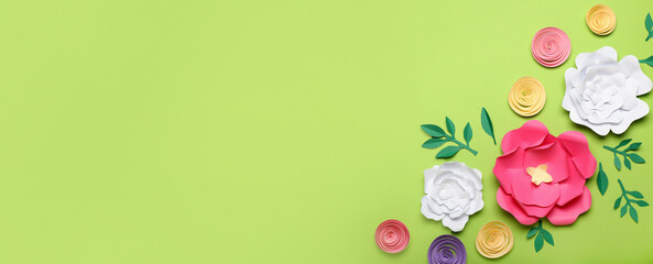 Beautiful handmade paper flowers on green background with space for text