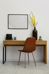 Stylish workplace with comfortable chair and gladiolus flowers