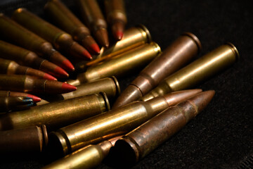 Pile M16 assault rifle cartridges on dark background.