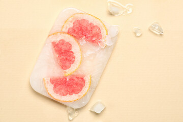 Fresh grapefruit frozen in ice on beige background
