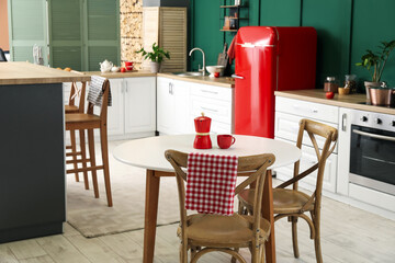 Interior of modern kitchen with dining table, stylish refrigerator and counters