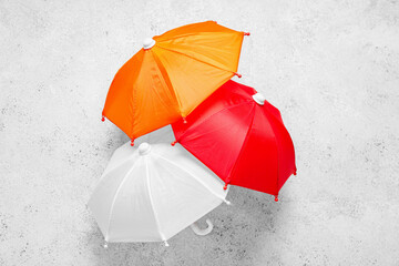 Different mini umbrellas on light background