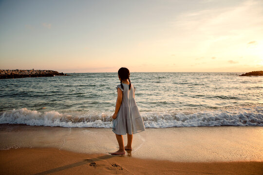girl children standing at sea beach against beautiful sunset light