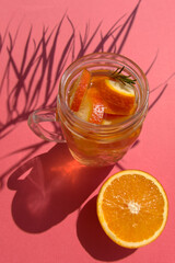 Orange fruit lemonade in mason jar with shadows from tropical plant