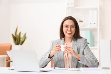 Young secretary drinking coffee in office