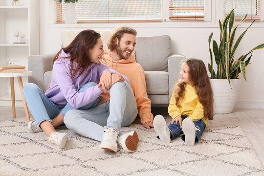 Young family sitting on soft carpet at home