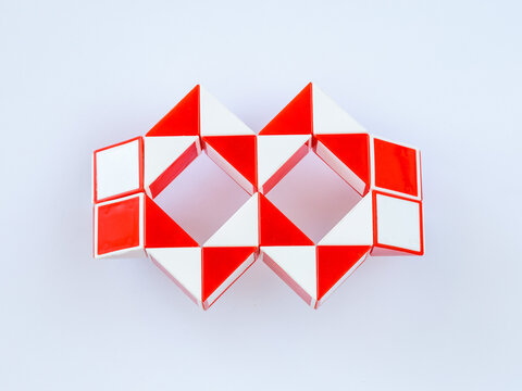 red and white bicolor magic snake Transformable twist puzzle in shape of carnival mask or glasses isolated on white background. it develops spatial thinking. - Powered by Adobe