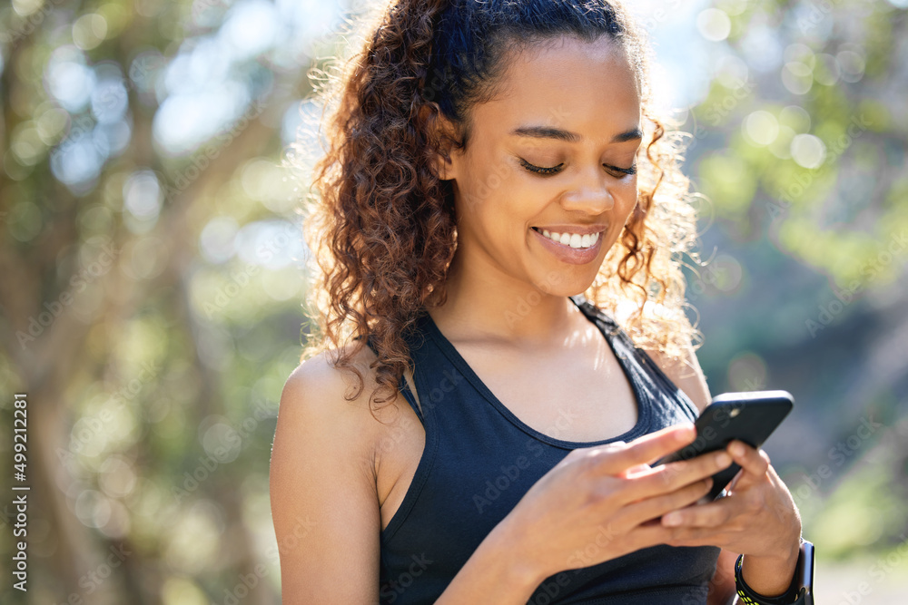 Poster setting the correct intentions. Shot of a young businesswoman using her smartphone before a run.