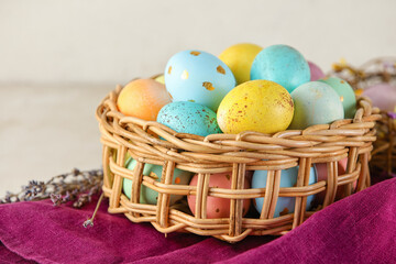 Wicker basket of painted Easter eggs on table
