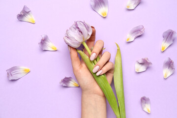 Woman with beautiful manicure holding tulip on color background, closeup