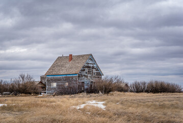 A moody sky over an old, abandoned blue home on the prairies of Saskatchewan 