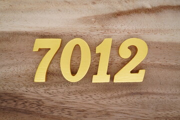 Golden Arabic numerals on a real brown and white wooden floor number 7012