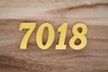 Golden Arabic numerals on a real brown and white wooden floor number 7018
