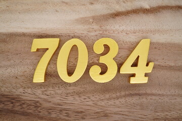 Golden Arabic numerals on a real brown and white wooden floor number 7034