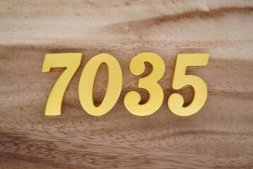 Golden Arabic numerals on a real brown and white wooden floor number 7035