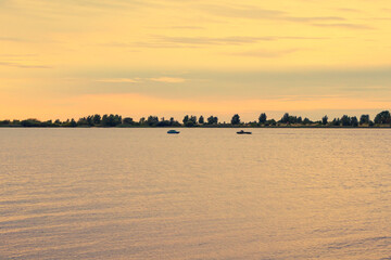 Naklejka premium Silhouettes of boats sailing in the distance against the background of the dark sky and the sea. Silvery Sunrise in the sea