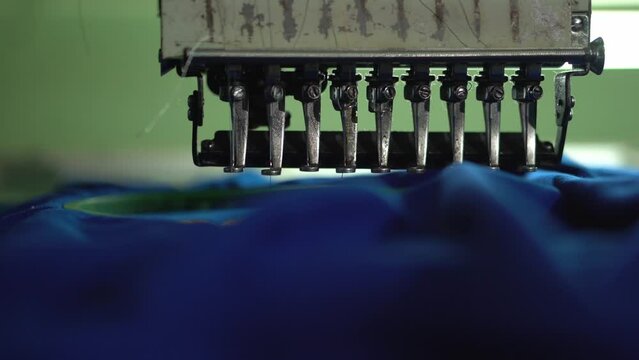 Close-up automatic embroidery machine is working at high speed. Embroidery machine embroidering logo on a T shirt.