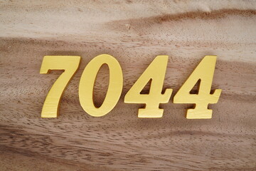 Golden Arabic numerals on a real brown and white wooden floor number 7044