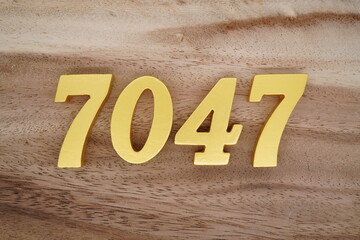 Golden Arabic numerals on a real brown and white wooden floor number 7047