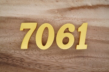 Golden Arabic numerals on a real brown and white wooden floor number 7061