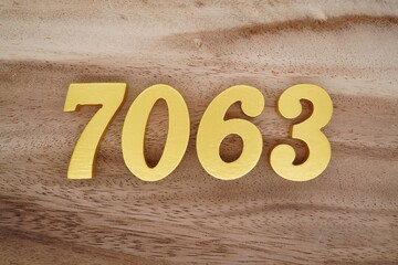 Golden Arabic numerals on a real brown and white wooden floor number 7063