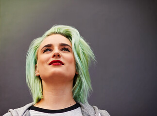 On top of the latest hair trends. Shot of a trendy young woman with mint green hair posing against...