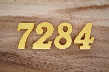 Golden Arabic numerals on a real brown and white wooden floor number 7284