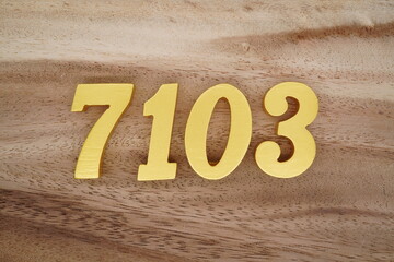 Golden Arabic numerals on a real brown and white wooden floor number 7103