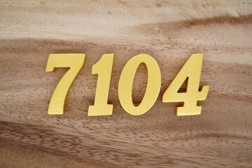 Golden Arabic numerals on a real brown and white wooden floor number 7104