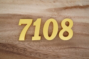Golden Arabic numerals on a real brown and white wooden floor number 7108