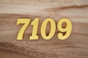 Golden Arabic numerals on a real brown and white wooden floor number 7109