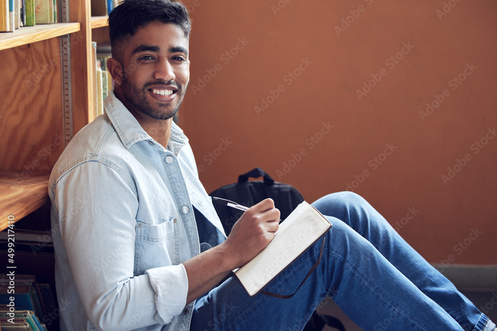 Poster Revision done right. Shot of a young man making notes in a library at university.
