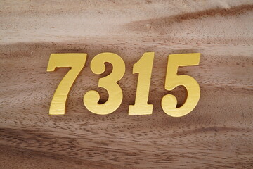 Golden Arabic numerals on a real brown and white wooden floor number 7315