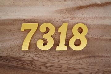 Golden Arabic numerals on a real brown and white wooden floor number 7318