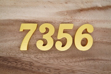 Golden Arabic numerals on a real brown and white wooden floor number 7356