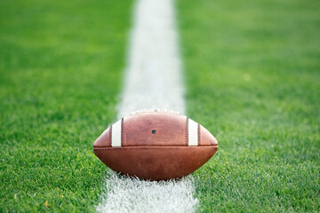 Close up view of an American Football sitting on a grass football field on the yard line. Generic...